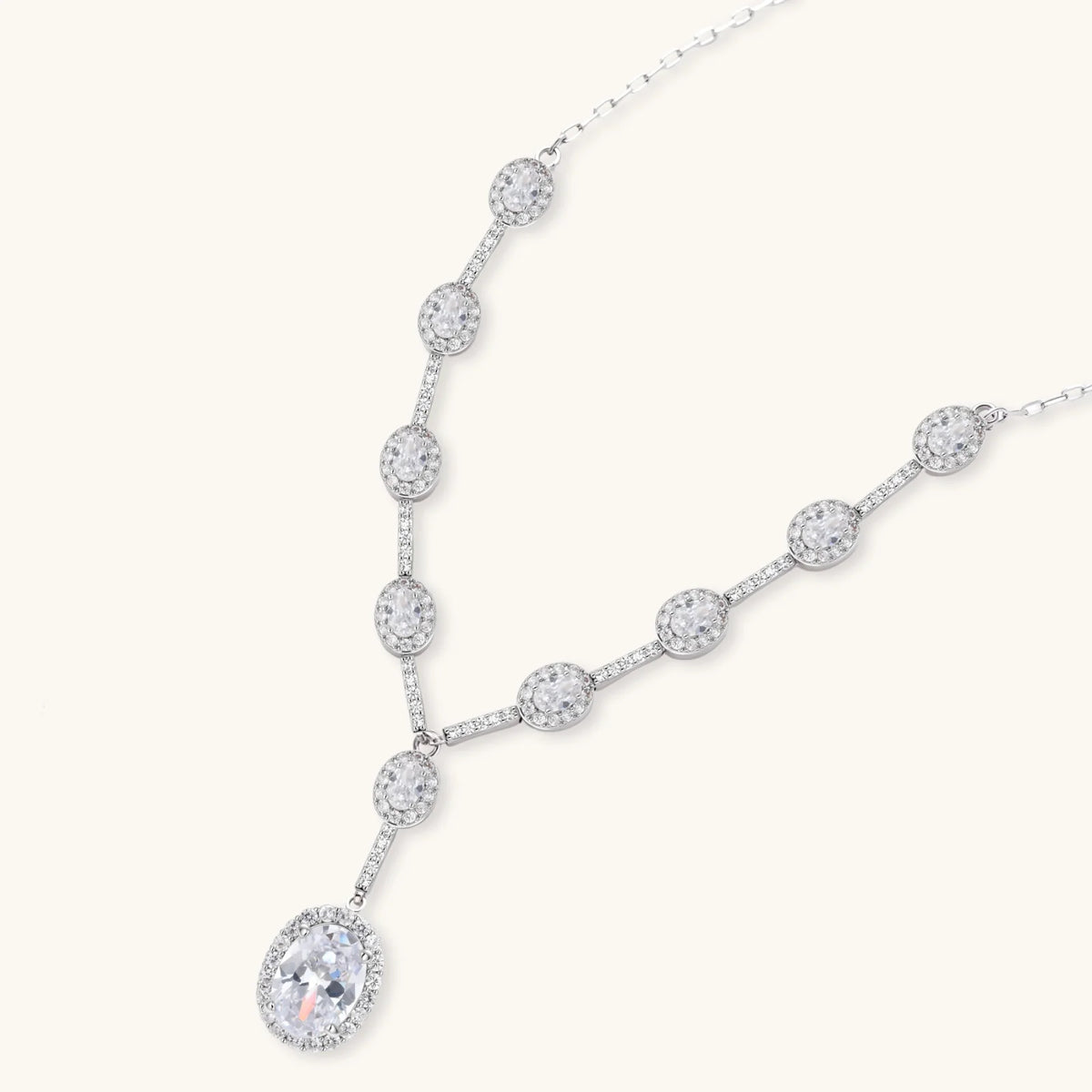 Elegant white gold plated jewelry set with oval cubic zirconia stones in halo settings, featuring Y-necklace and drop earrings.